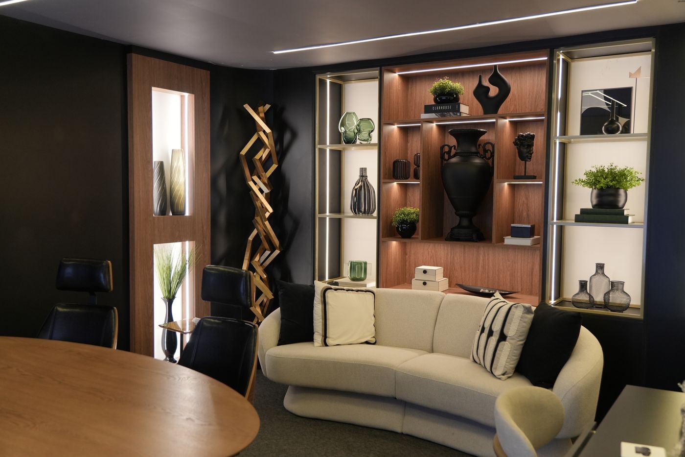 Lounge de espera com sofá curvo e estante iluminada